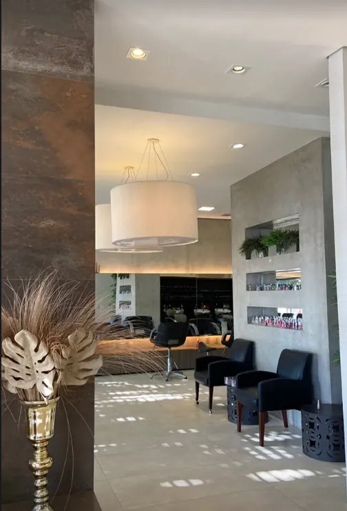 Salão principal da casa de Balneário Camboriú: parede de concreto, luminárias de tecido, cadeiras de couro preto e luz natural