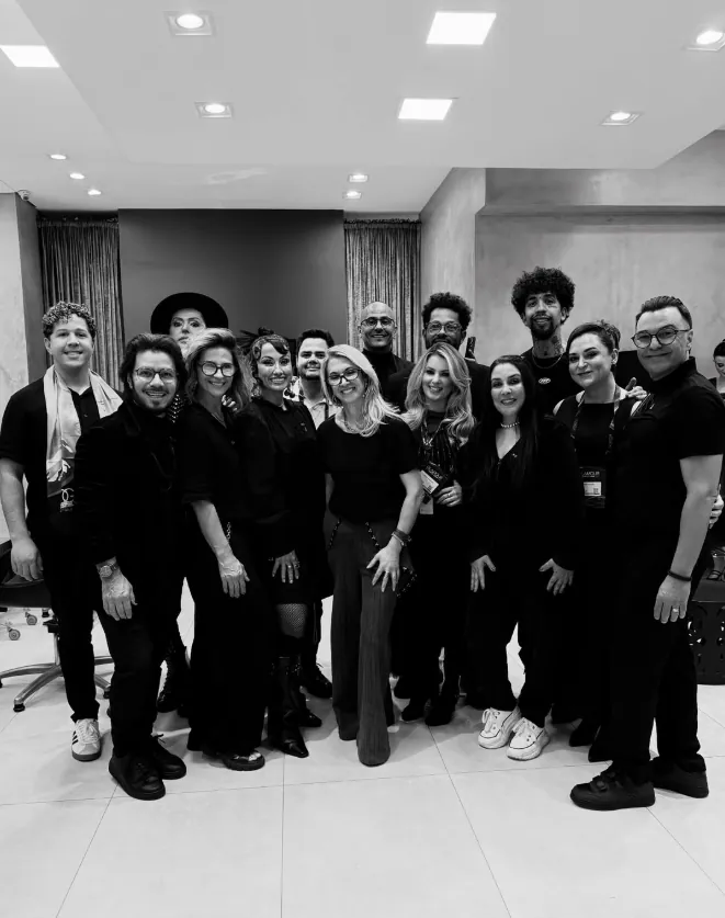 Foto em preto e branco da equipe do Léia Salão, cerca de quinze pessoas vestidas de preto dentro do salão