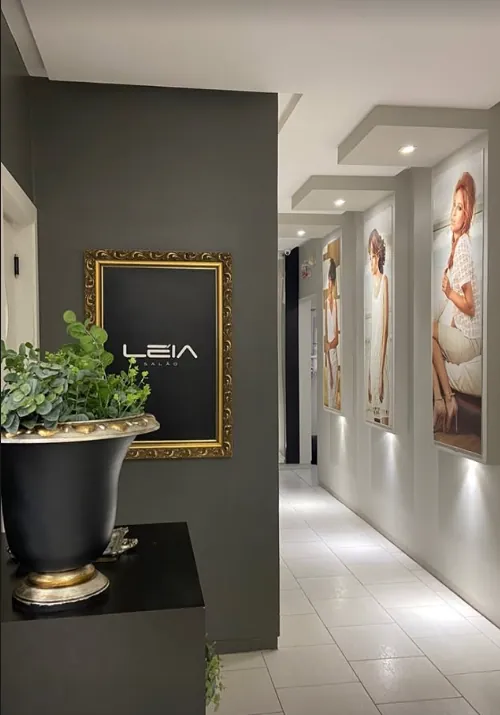 Recepção com parede grafite, quadro de moldura dourada com o logo Léia Salão e corredor com painéis de campanhas do salão